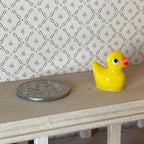 1:12 scale miniature yellow bath duck with orange beak, will not float, shown on a table beside a coin