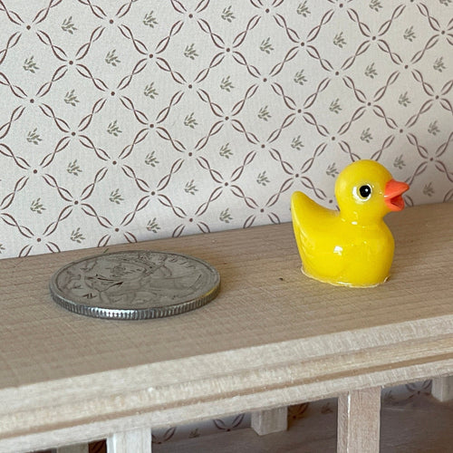 1:12 scale miniature yellow bath duck with orange beak, will not float, shown on a table beside a coin