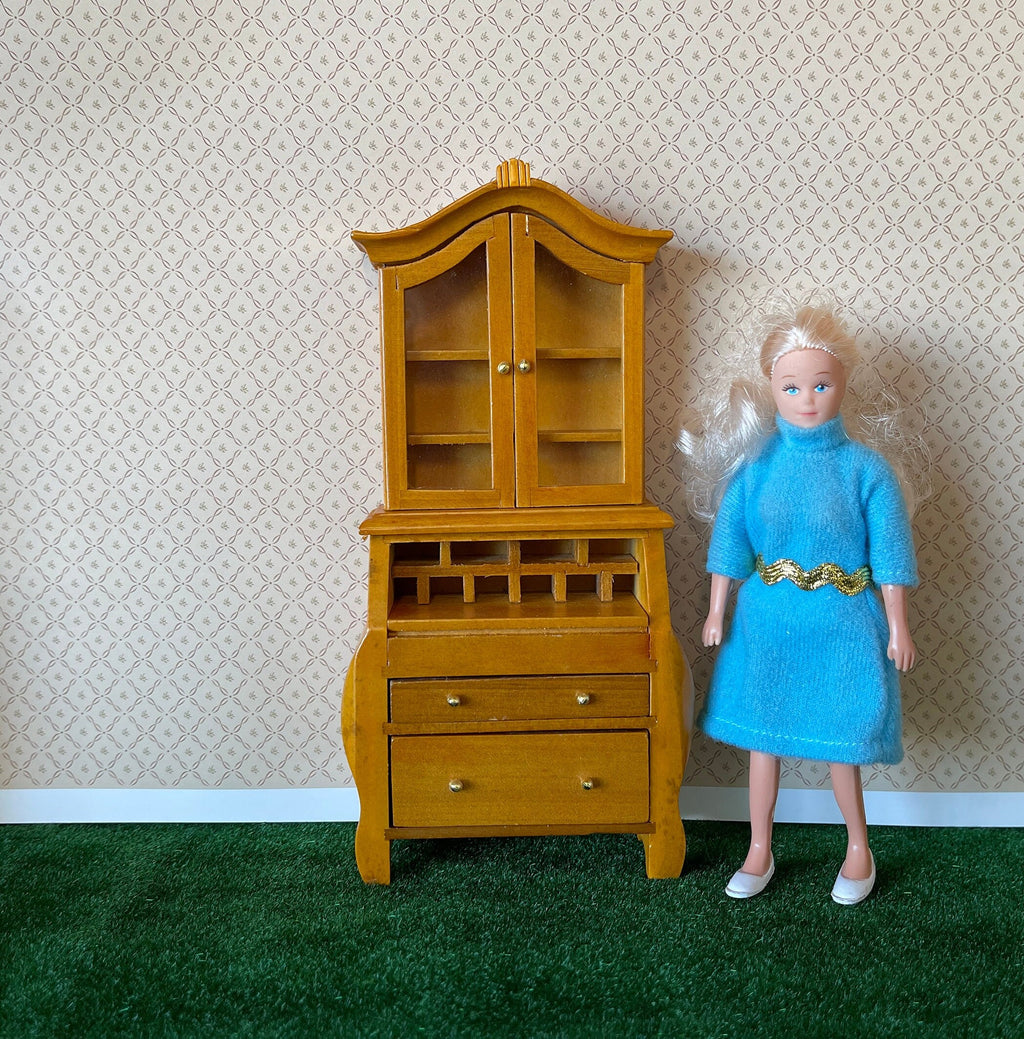 1:12 scale miniature wood secretary desk with glass door bookcase top, honey finish, shown beside a doll for scale