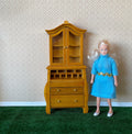 1:12 scale miniature wood secretary desk with glass door bookcase top, honey finish, shown beside a doll for scale