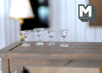 1:12 scale miniature clear wine glasses, set of 4, wide bowls on stems, shown on a gray wood table