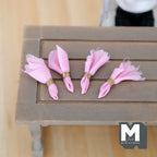1:12 scale miniature cloth napkins in pink with gold napkin rings, set of 4, shown in a row on a gray wood table