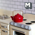 1:12 scale miniature enamel kettle in red with white speckles, gold handle and fixed lid, on a cream stove