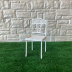 1:12 scale miniature metal garden chair in white with ornate openwork back and woven seat, on green turf