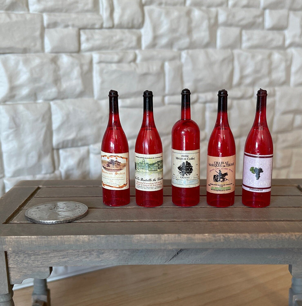 1:6 scale miniature red wine bottles with assorted labels, set of 5, shown in a row on a table beside a coin