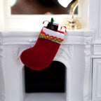 1:12 scale miniature filled Christmas stocking in red with a patterned cuff and candy canes, shown hung on a white fireplace