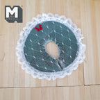 1:12 scale miniature Christmas tree skirt in green with white lace edge and red bow, shown flat on a wood floor