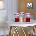 1:12 scale miniature fruit jam jars with cloth covered lids, set of 3, red and orange, shown on a round white table
