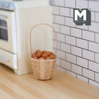 1:12 scale miniature brown eggs in a rope basket with tall handle, shown on a wood floor by a white tiled wall