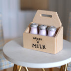 1:12 scale miniature wood milk crate with 3 glass milk bottles, carry handle and printed milk label, on a white table