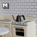 1:12 scale miniature black metal gooseneck coffee drip kettle, shown on a cream stove in a tiled kitchen