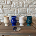 1:12 scale miniature ceramic urn vases in white, cream, blue and green, set of 4, lined up on a wood bench beside a coin