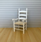 1:12 scale miniature white wood ladder back armchair with a woven natural seat, shown on a wood floor