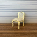1:12 scale miniature wood French style vanity chair in cream with a cane look back and curved legs, on a wood floor