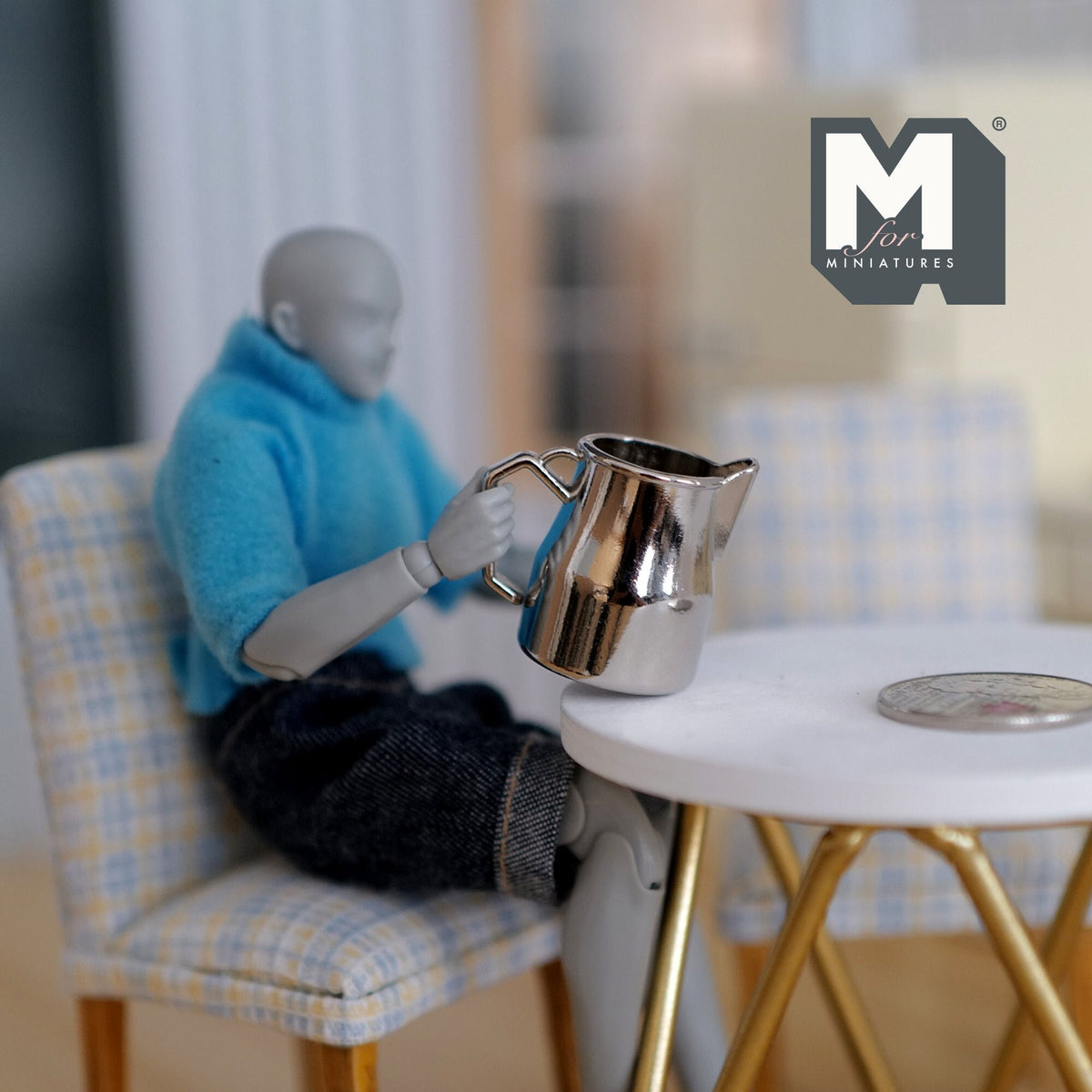 1:12 scale miniature silver metal jug with handle and spout, shown held by a seated poseable figure