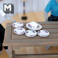 1:12 scale miniature ceramic plate set with oval platter, cover dome and purple floral rim, set of 6, on a gray table