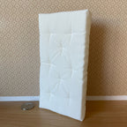 1:12 scale miniature tufted single mattress in white, shown standing against a wall beside a coin for scale
