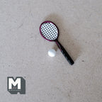 1:12 scale miniature tennis racket and ball set in black and red with white ball, shown on a gray surface