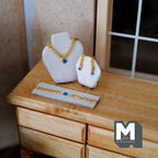 1:12 scale miniature jewelry set on stands in blue, necklace, earrings and bracelet with gold chain, on a wood dresser