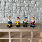 1:12 scale miniature garden gnome figurines with pointy hats, set of 4, colorful painted outfits, on a wood shelf by a coin