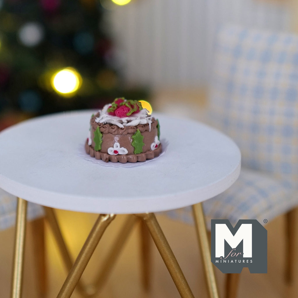 1:12 scale miniature Christmas chestnut cake with chocolate sides, holly and cream topping, non edible, on a white table