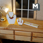 1:12 scale miniature jewelry set on stands in red, necklace, earrings and bracelet with gold chain, on a wood dresser