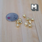 1:12 scale miniature cross cut jingle bells in gold, set of 10, shown on a wood surface beside a coin for scale