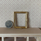 1:12 scale miniature ornate picture frame in gold, shown empty on a wood shelf beside a coin for scale