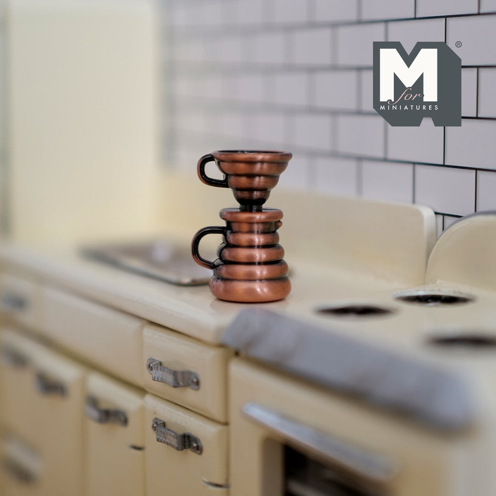 1:12 scale miniature metal coffee dripper with server in copper with black handles, shown on a kitchen stove