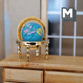 1:12 scale miniature world globe in blue on an ornate gold metal stand, shown on a wood dresser by a window