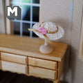 1:12 scale miniature straw cartwheel hat with pink roses on a wood stand, white wide brim, shown on a wood dresser