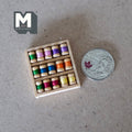 1:12 scale miniature sewing thread spools in a wood tray, 15 spools in assorted colors, shown beside a coin for scale