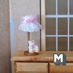 1:12 scale miniature bear table lamp with frilly white drum shade and pink bow, non working, shown on a wood dresser