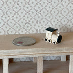 1:12 scale miniature cast resin toy locomotive in white and black, shown on a wood shelf beside a coin for scale