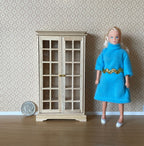 1:12 scale miniature unpainted wood bookcase cabinet with 2 glazed doors and 6 shelves, shown beside a figure and coin
