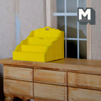 1:12 scale miniature wood mail holder in yellow with 3 stepped slots, shown on a wood dresser