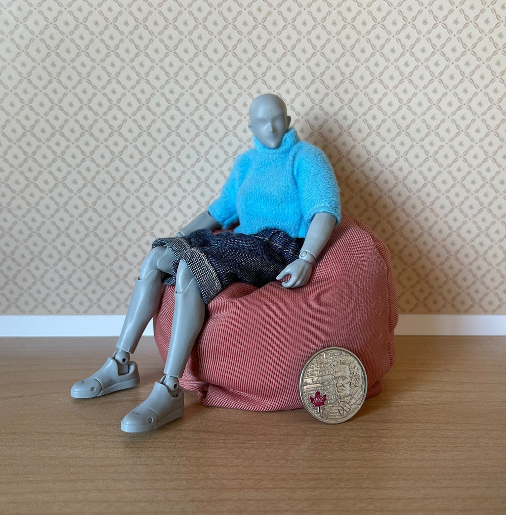 1:12 scale miniature fabric bean bag chair in dusty pink, shown with a poseable figure seated on it and a coin