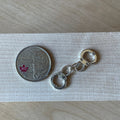 1:12 scale miniature metal handcuffs with chain link in silver tone, non working, shown beside a coin for scale