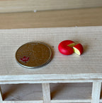 1:12 scale miniature round cheese and cheese wedge, set of 2, red wax rind with yellow center, on a shelf beside a coin