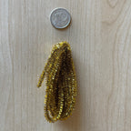 1:12 scale miniature Christmas tinsel garlands in gold, set of 2, shown bundled on a wood surface beside a coin