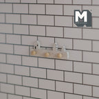 1:12 scale miniature cottage style hat and coat rack with 3 pegs, white, shown mounted on a subway tile wall