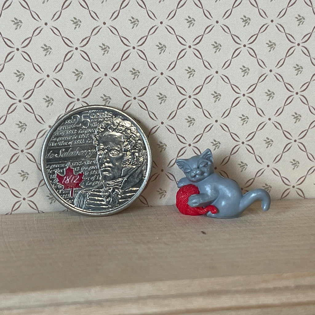 1:12 scale miniature gray kitten playing with a red yarn ball, shown beside a coin for scale