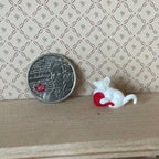 1:12 scale miniature white kitten playing with a red yarn ball, shown on a wood shelf beside a coin for scale