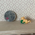 1:12 scale miniature orange kitten playing with a green yarn ball, on a wood shelf beside a coin for scale