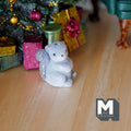 1:12 scale miniature gray baby squirrel figurine with flocked skin, sitting, shown by Christmas gifts under a tree
