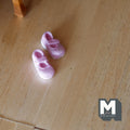 1:12 scale miniature baby shoes in pink with straps, 1 pair, shown on a light wood floor