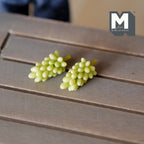 1:12 scale miniature green grape bunches, set of 2, shown lying on a gray wood table