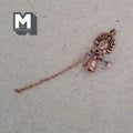 1:12 scale miniature metal house bell in bronze with scroll bracket and pull chain, shown laid on a tan surface