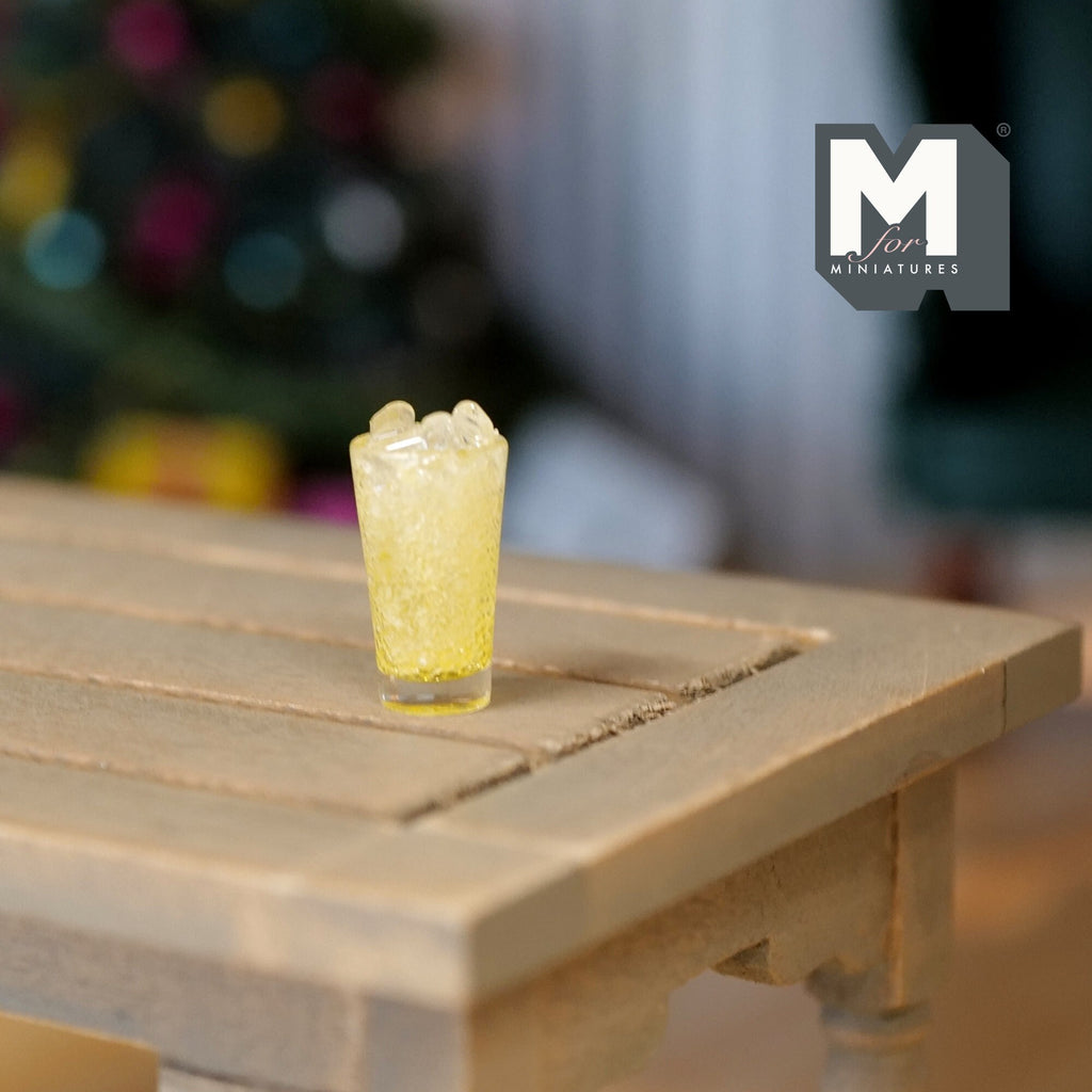 1:12 scale miniature glass of iced lemonade, pale yellow drink with ice cubes, shown on a wood table