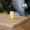 1:12 scale miniature glass of iced lemonade, pale yellow drink with ice cubes, shown on a wood table